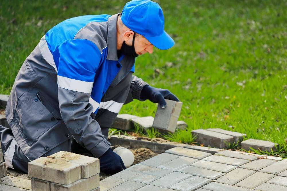 Masonry professional installing pavers in a garden, showcasing local craftsmanship and attention to detail in masonry services for Etowah properties.
