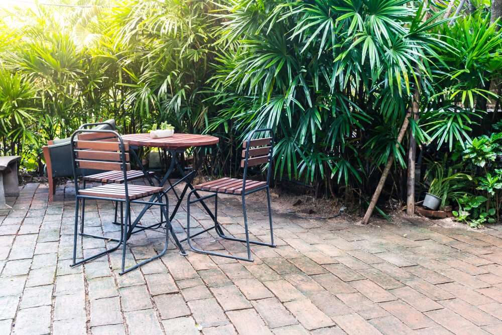 Paver patio with a round table and chairs surrounded by lush greenery, illustrating inviting outdoor gathering spaces that enhance biodiversity in Etowah, NC.