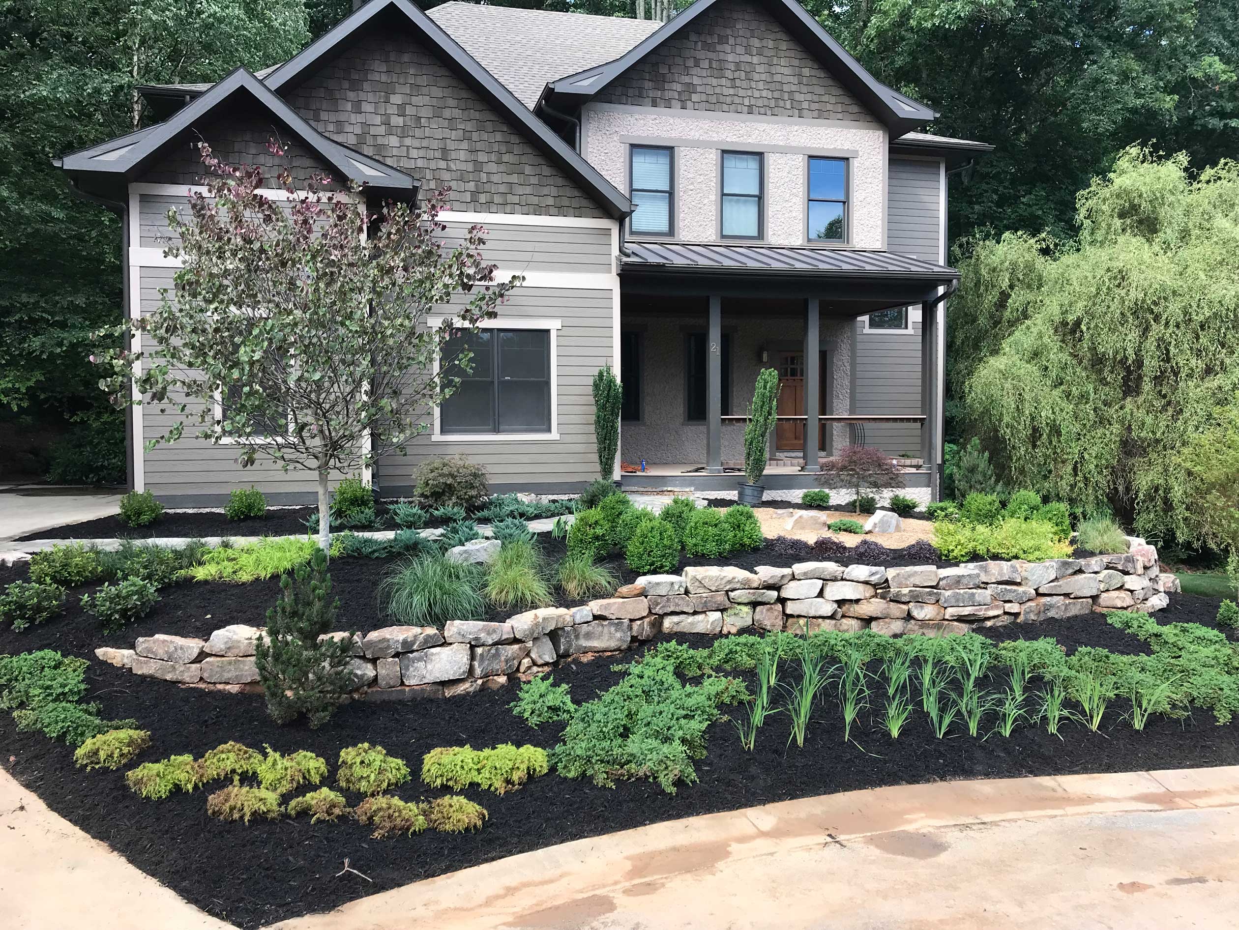 Natural stone retaining wall integrated with a residential landscape Natural stone retaining wall integrated with a residential landscape