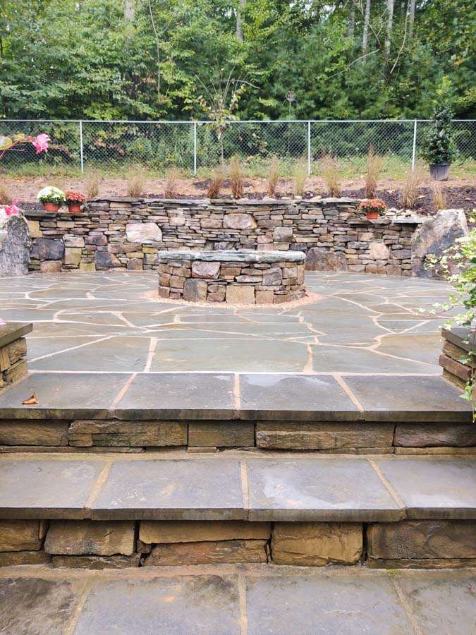 Laughter Family Hardscapes Hardscaping Services Buncombe County NC -01 The pictures depicts a hardscape of pavers that pave stair, a retaining wall and a fireplace.