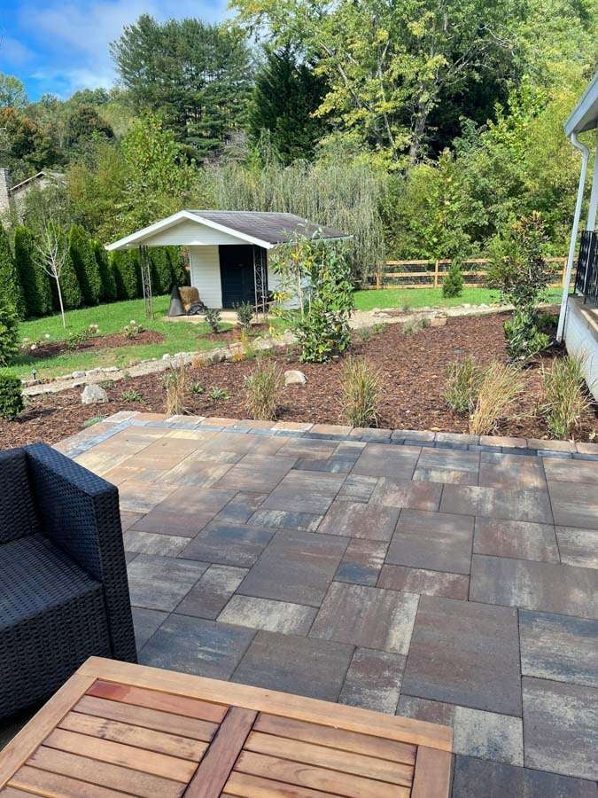 Laughter Family Hardscapes Hardscaping Services Buncombe County NC -05 The image depicts a square backyard patio that has been paved with rectangle pavers.