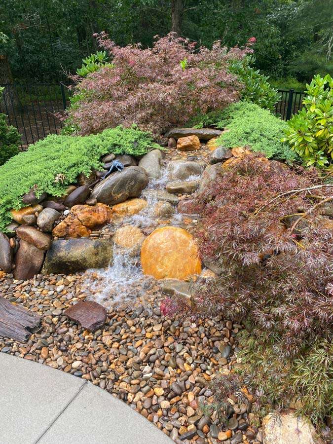 Laughter Family Hardscapes Hardscaping Services Buncombe County NC -11 The image depicts a expertly crafted rock waterfall that flows into a river rock return.